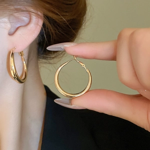 Detailed close-up of high-polish gold hoop earrings with minimalist circular design
