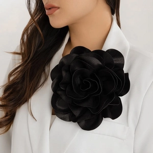 Detail of large black satin rose brooch pinned to a white suit lapel for a classy look