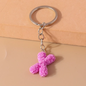 Detail of pink resin letter X keychain with textured rose carvings and silver metal ring