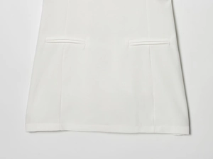 Dettaglio dell'orlo del vestito bianco con cuciture rifinite e tasca integrata
