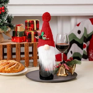 Knitted Christmas gnome wine bottle cover with red hat and white beard on a tray