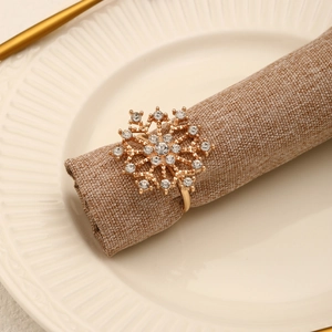 Rond de serviette flocon doré avec cristaux sur serviette en lin beige et assiette