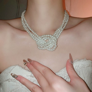 Detailed view of white triple-layer knotted pearl necklace on model for elegant styling