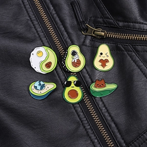 Close-up of six creative avocado enamel pins styled on a black leather jacket lapel