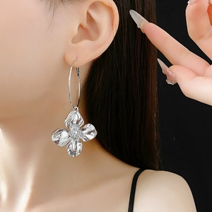 Macro detail of large silver metallic flower hoop earrings worn on a model's ear