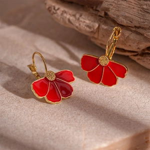 Detail of red enamel flower earrings with gold metal frame on a natural stone base
