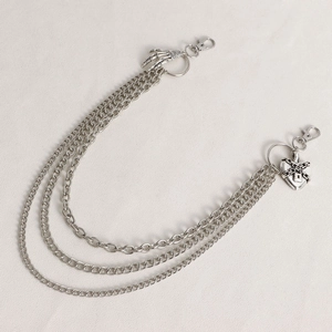 Detail of silver heart-shaped padlock and skeleton hand charms on layered punk chain