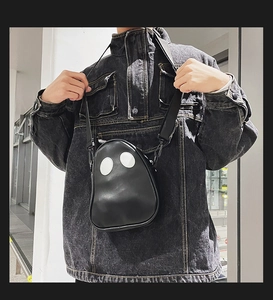 Detail of creative ghost-shaped crossbody bag in black PU leather worn by a model