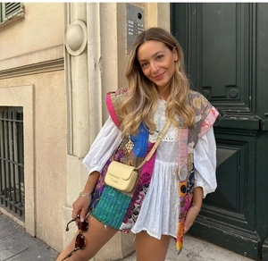 Close-up of Bohemian patchwork quilted vest paired with a white dress in street style
