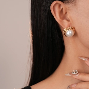 Détail d'une boucle d'oreille vintage en métal doré torsadé avec perle ronde nacrée