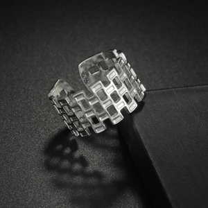 Polished silver stainless steel open ring with geometric cut-out pattern on dark surface