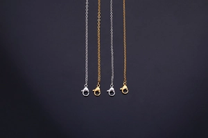 Vertical display of gold and silver cross chain necklaces with lobster clasps on a dark base