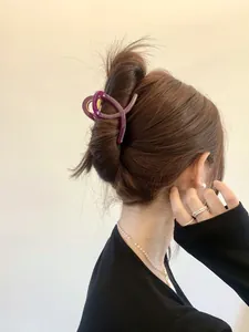 Gros plan sur une pince à cheveux en résine violette avec design croisé et fini brillant