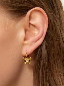 Close-up of a gold butterfly hoop earring with a sparkling center zircon on the ear