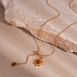 Macro shot of gold sunflower pendant with tiger eye stone on natural stone base