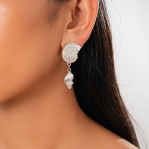 Close-up of shell stud and conch pendant earring in silver metal texture on ear