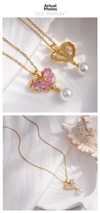 Macro detail of gold plated heart pendant with pink zircon and white pearl drop