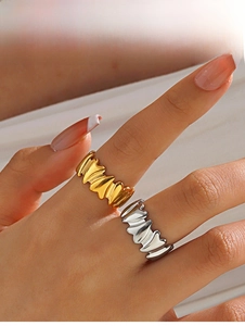 Close-up of gold and silver irregular wavy rings on model hands with white fabric backdrop