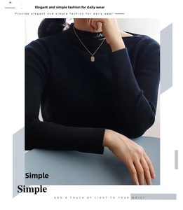 Detail of a minimalist gold-plated rectangular letter pendant necklace on black knitwear