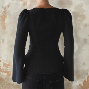 Vue arrière du haut moulant noir avec manches bouffantes et poignets évasés élégants