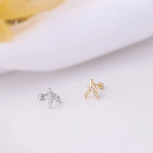 Macro shot of fishtail stud earrings with sparkling cubic zirconia in gold and silver