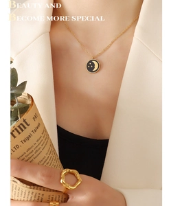 Close-up of gold star and moon pendant necklace with irregular wavy gold band ring