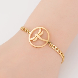 Detail of a gold titanium steel bracelet with a hollow dragonfly charm worn on the wrist
