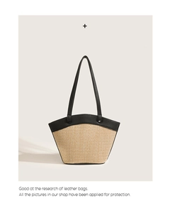 Detail of handwoven straw tote featuring premium black leather trim and handles