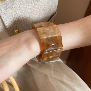 Detail of acrylic marble cuff bracelet worn with beige tweed fabric for luxury style