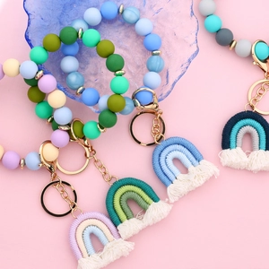 Colorful silicone bead bracelet keychain with rainbow fringe charms on pink background