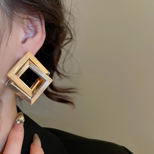 Detailed view of oversized geometric square earrings with gold metal and black resin inlay