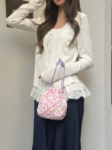 Detail of pink floral quilted fabric bag with purple drawstring and brand label