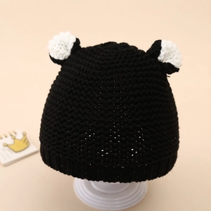 Detail of baby winter knit hat in black with white decorative ears and ribbed texture
