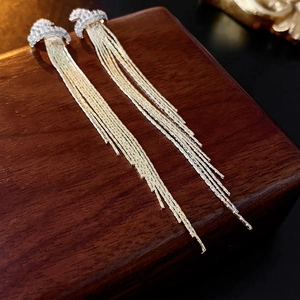 Close-up of elegant long tassel earrings with sparkling crystals on a wooden display box
