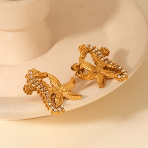 Vue macro de boucles d'oreilles hippocampe et étoile de mer dorées avec zircons blancs