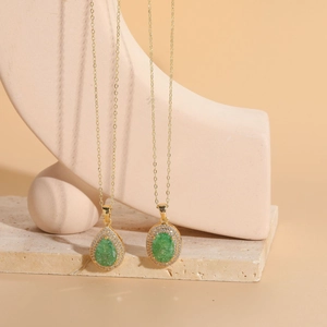 Detail of teardrop and oval emerald zircon pendants on 14K gold plated necklaces