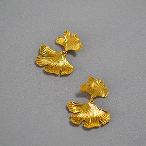 Macro detail of golden ginkgo leaf earrings showing intricate metal vein textures