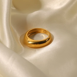 Detailed close-up of polished 18k gold plated stainless steel ring on beige silk background