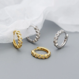 Macro detail of gold and silver heart-shaped hoop earrings with sparkling cubic zirconia