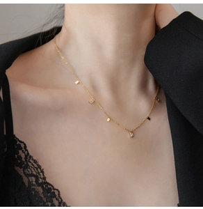 Close-up of gold chain necklace featuring polished rectangular pendants and clear zircons