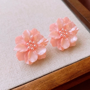 Detailed macro shot of sakura pink layered acrylic flower studs with pearl centers