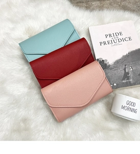Close-up of three leather passport envelopes in blue, red, and pink on a white rug