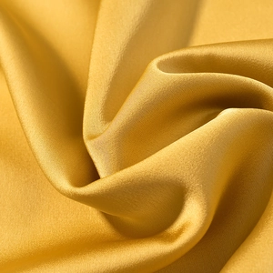 Detail of golden yellow silk satin fabric with elegant drapes and smooth luxury texture