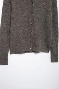 Detail der grauen Strickjacke mit Metallknöpfen und gerippter Manschettenstruktur