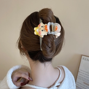Detail of cute cartoon acrylic hair claw clip worn on a woman's hair with a secure metal spring