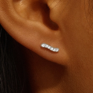 Macro shot of s925 silver wavy cartilage earring with zircon stones on female model ear