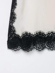 Detailed close-up of white satin fabric with delicate black eyelash lace trim