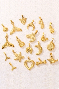 Detailed collection of 18k gold plated stainless steel charms on beige texture background
