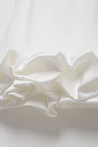 Detailed view of the elegant pearl white satin dress with ruffled hem and silky texture