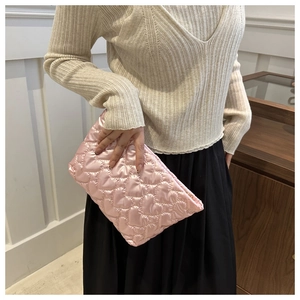 Close-up of pink quilted heart-pattern handbag held by a model for a stylish look